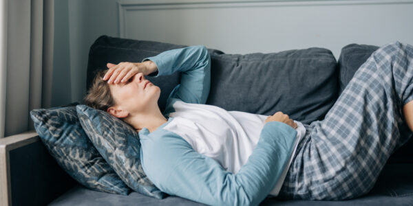 Woman laying on sofa with headache from TMJ in New Jersey