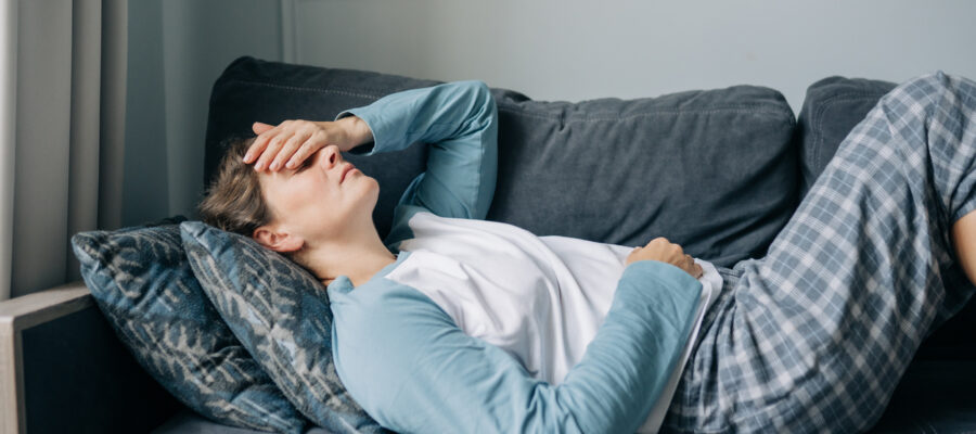 Woman laying on sofa with headache from TMJ in New Jersey