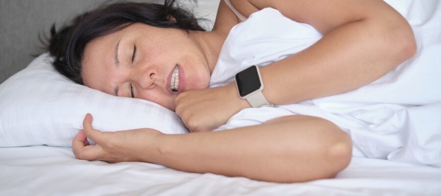 Woman clenching her teeth strongly in her sleep, contributing to her TMJ pain and other symptoms.